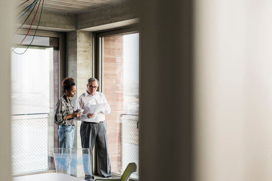 Senior manager discussing documents with young coworker 