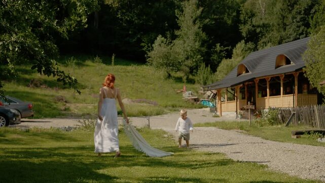 A woman walks with her little boy in front of a traditional house in Bucovina. They share smiles and laughs while spending time together outdoors.