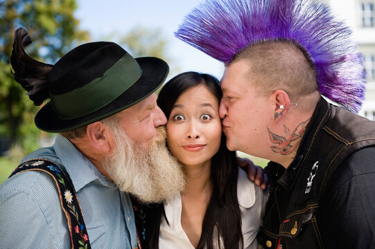 Germany, Bavaria, Upper Bavaria, Two men kissing Asian woman on cheek, portrait 