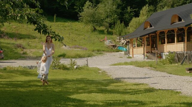 A woman and her little boy enjoy their time playing outside a traditional house in Bucovina. They share smiles and laughter while exploring the area.