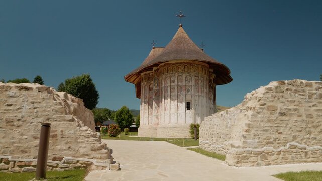 Humor Monastery in Bucovina Romania shows beautiful old paintings on its walls. Visitors can walk around the area and take in the history of this site.
