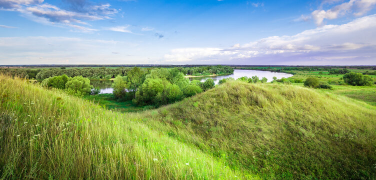 Green hills roll gently under blue sky
