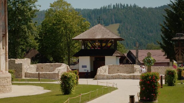 Visitors explore the old walled courtyard at Humor Monastery in Bukovina. The site features ancient paintings and scenic views of the surrounding landscape.