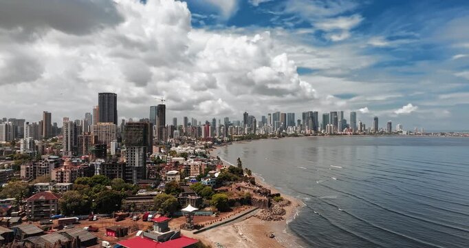 Beautiful aerial view of Mumbai city skyline along the Arabian Sea, featuring modern high-rise buildings, sandy beaches, and a vibrant coastal landscape under a bright blue sky.