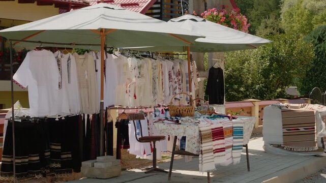Visitors explore a stall with traditional clothes in Bucovina, showcasing handmade items and local culture. This market area reflects Romanian heritage and craftsmanship.