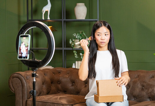 Asian woman recording a beauty makeup tutorial with smartphone and ring light