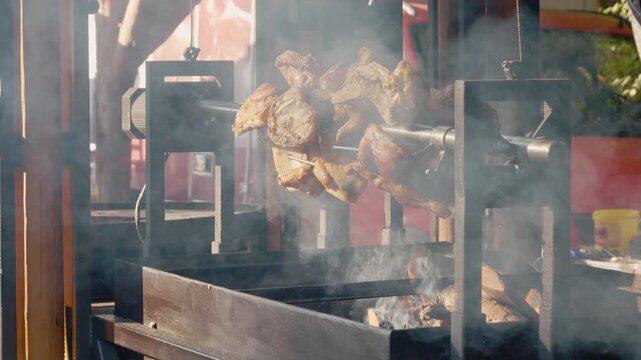 Grilled chickens rotate over hot flames at a street food festival in Bukovina. The aroma fills the air as people enjoy this popular meal during the event.