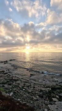 Vertical video of a panoramic horizon line of an breathtaking sky at sunrise or sunset with the sunbeams through clouds over the Mediterranean Sea from the coast
