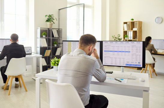 Man employee analyst faces stress at computer. Overworked office worker reviews finance spreadsheets, worried about mistakes and deadlines. Clear workplace burnout and pressure concept.