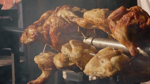 Chickens cook on a rotating grill at a street food festival in Bukovina. The aroma fills the air as people gather to enjoy delicious grilled meals.