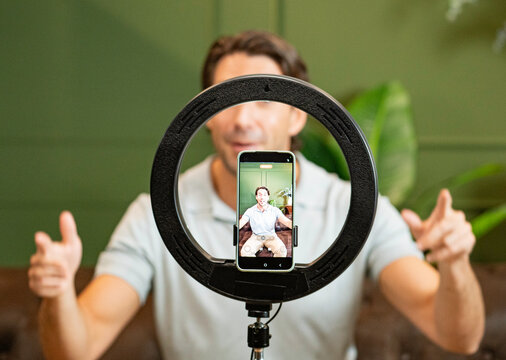 Man recording a video for social media using a phone and ring light