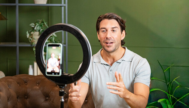 Man recording a video for social media with a smartphone and ring light