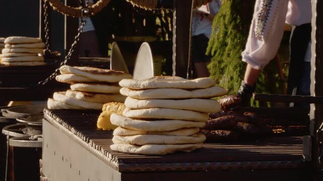 Visitors enjoy grilled potato and polenta pies at a street food festival in Bukovina. The aroma fills the air as people gather to taste these delicious treats.