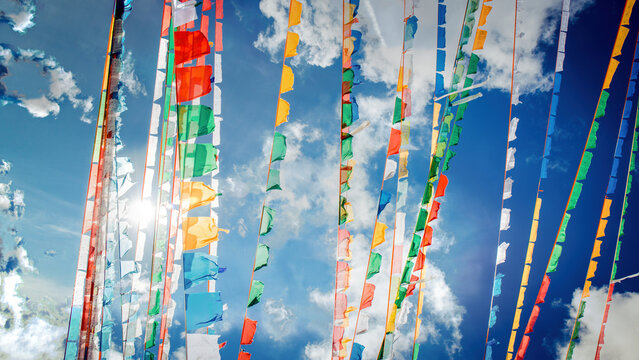 Colorful Tibetan Prayer Flags Fluttering Against a Bright Blue Sky with Sunlight
