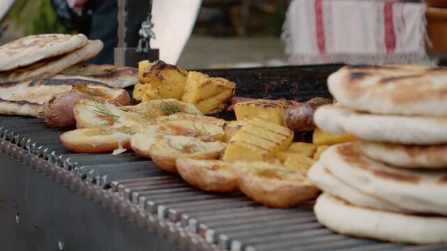 Visitors enjoy grilled potato and polenta pies at a bustling street food festival in Bukovina. The smell of cooked food fills the air as people gather around.