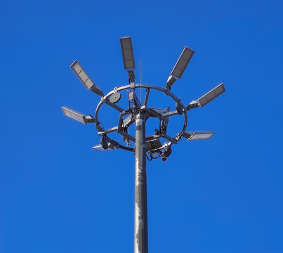 High mast floodlight pole with multiple LED lamps against blue sky for industrial lighting concept