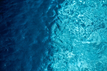 Abstract background of crystal clear blue water with sunlight reflections and a smooth transition between deep and turquoise blue tones. © carloskoblischek