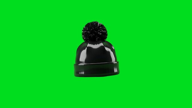 A sleek black winter beanie hat featuring a fluffy pompom on green screen