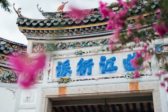 PENANG, MALAYSIA - JUN 02, 2026: Decorative entrance gate of Cheong Fatt Tze Blue Mansion framed by pink flowers in George Town, Penang, Malaysia.