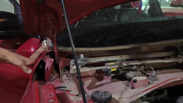 Mechanic removes damaged front windshield from car at automotive repair garage. Footage shows windshield replacement and auto glass repair process, highlighting vehicle maintenance