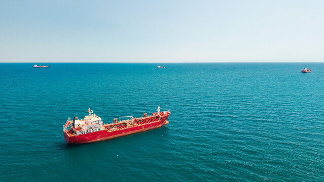 Red tanker ship sailing in calm turquoise sea viewed from aerial drone