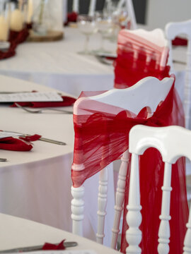 D&eacute;coration de salle de r&eacute;ception de mariage en rouge et blanc avec tables dress&eacute;es, fleurs, bougies et chaises d&eacute;cor&eacute;es