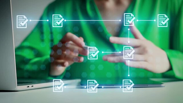 A person is working at a desk with a laptop and tablet. They use hands to interact with digital elements showing document icons. Light comes from a window.