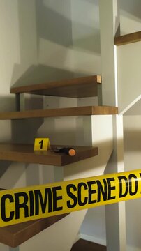 Yellow crime scene tape securing a residential staircase where a knife and an evidence marker are placed on a step. Indicating a recent and violent criminal act under investigation by law enforcement