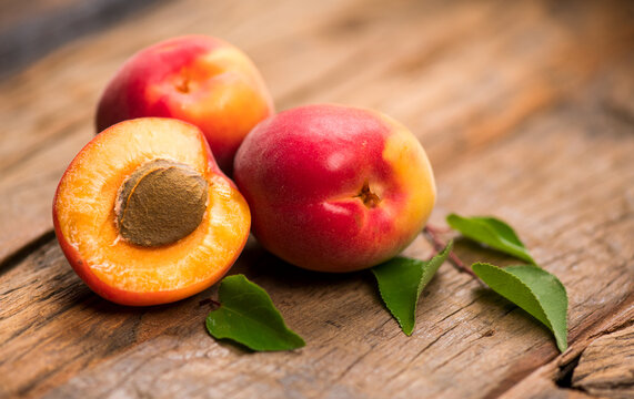 Apricots, close-up of fresh organic apricots fruits on a rustic wooden table. Fresh bio apricot with leaves closeup, top view. 