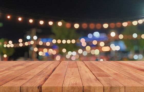 Empty wooden table top with blurred festive bokeh lights at night market
