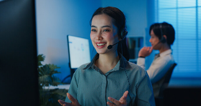 Gen z Asia young call center team or customer support service executive use computer and microphone headset work technical e commerce support in late night office. Telemarketing or sales job concept.
