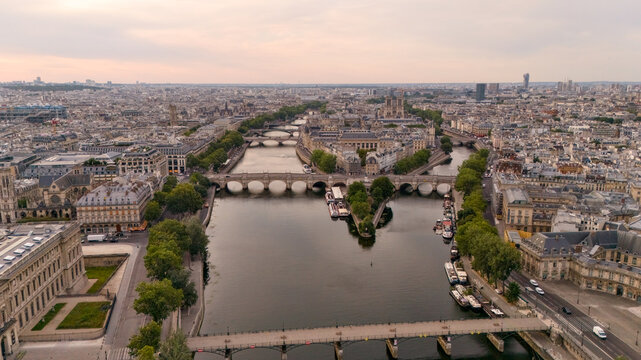 Drone footage captures a long river bend crossed by a bridge amid dense city surroundings