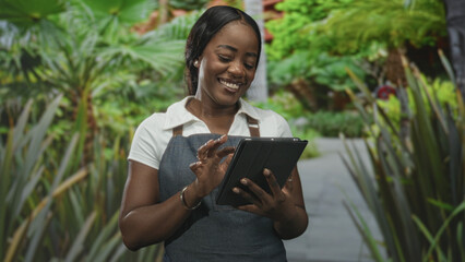 Woman in apron tapping tablet with smiling hands on a garden path surrounded by plants in a forest setting  friendly joy. © Krakenimages.com