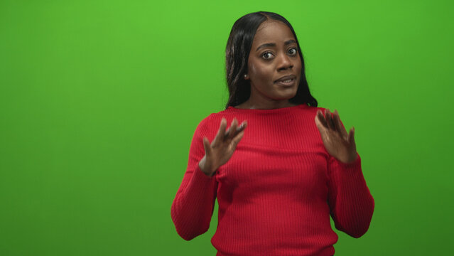 Woman in red sweater gesturing with hands while speaking to camera in a green studio set; focused explanation clarity.