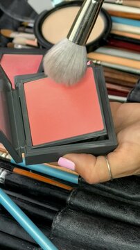 Makeup brush picks up blush from a cosmetic palette in close up, professional beauty tools, makeup preparation, color selection.