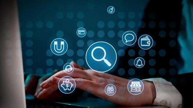 A hand is using a laptop while search icons and symbols float around. The setting is dimly lit, creating a focus on the hand and the screen. This scene shows online activity and technology use.