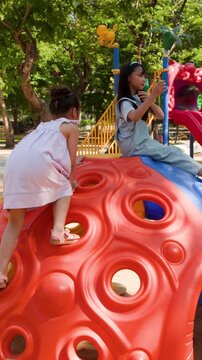 Two Young Asian Girls Playing on Climbing Dome at Lumpini Park
