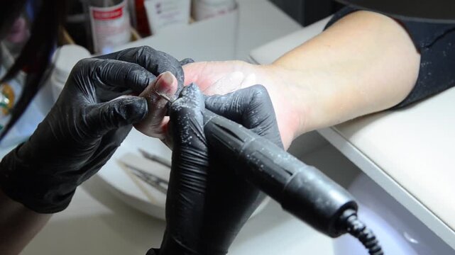 Manicurist uses a ball drill bit to treat the cuticle area during professional hardware manicure. Close-up nail care procedure in a beauty salon.