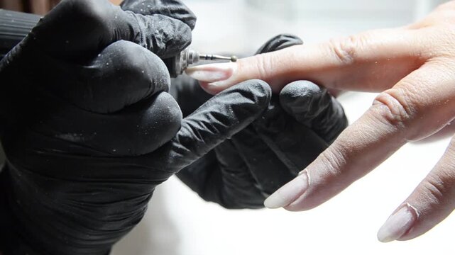 Manicurist uses a ball drill bit to treat the cuticle area during professional hardware manicure. Close-up nail care procedure in a beauty salon.