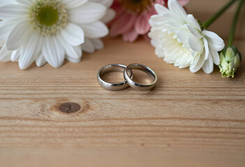Fototapeta premium Wedding rings and marriage commitment, love and romance celebration, engagement and anniversary with flowers on wood
