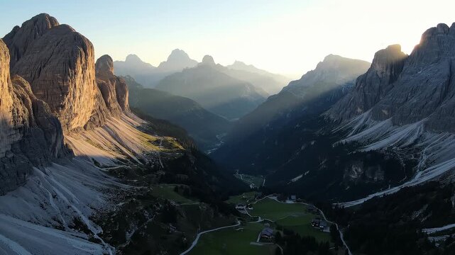 Golden sunlight illuminates towering cliffs above a deep mountain valley