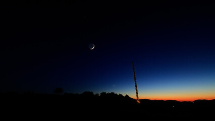 Moon on a twilight sky with stars, planets and landscape mountain silhouettes. © astrosystem
