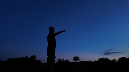 Silhouette of a person in nature observing night sky, Moon, stars and planets from a remote location. © astrosystem