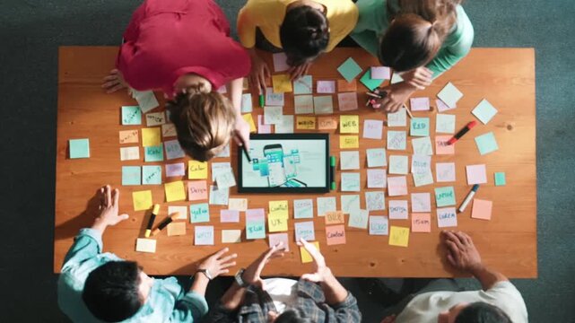 Aerial view of developer team discussing and showing digital program and writing by using Ux Ui design. Top down view of business people develop wireframe prototype for phone and computer. Symposium.