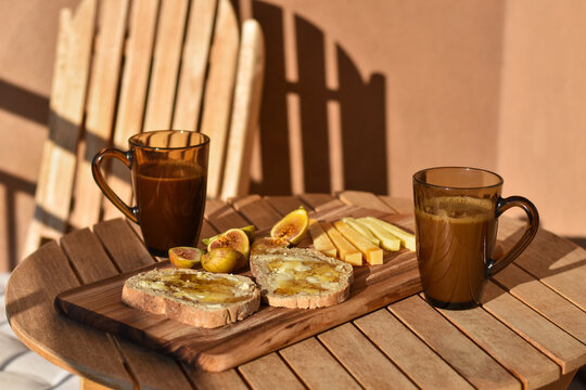 Outdoor breakfast with bread and honey, cheese, figs and coffee
