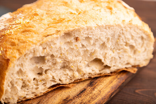 Slice of homemade bread with butter on plate on brown wooden, close up, side view, selective focus.
