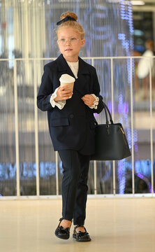 A stylish little girl in a dark blue business suit and glasses.