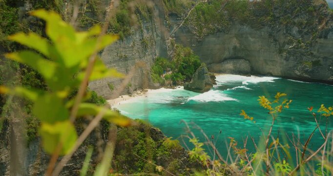 Hidden tropical beach between steep cliffs with clear turquoise ocean in Nusa Penida Island Bali