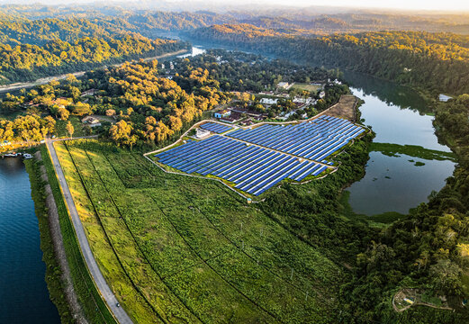 Rangamati, Chittagong Division, Bangladesh - 14 December 2024: Aerial view of a solar power plant nestled among green hills beside Kaptai Lake, featuring rows of photovoltaic panels.