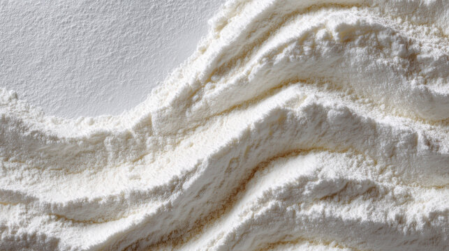 A close-up, high-angle view of a smooth, white powder artfully arranged in undulating waves, suggesting texture and purity.